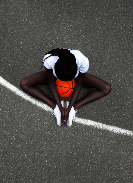 Young sporty afro-american model with orange basketball at stadium - Foto, Imagen