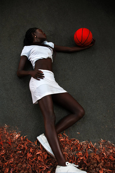 Slim young afro-american girl posing with basketball on asphalt - Foto, Imagen