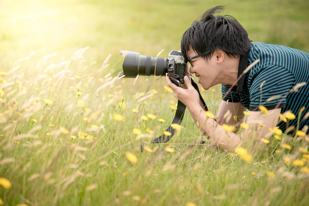 Jeune photographe asiatique prenant des photos sur le champ vert
 - Photo, image