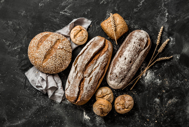 Bakery - rustic crusty loaves of bread and buns on black - Фото, зображення