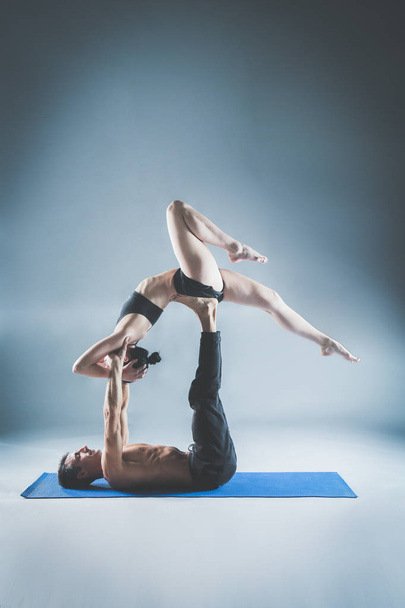 Young couple practicing acro yoga on mat in studio together. Acroyoga. Couple yoga. Partner yoga. - Фото, зображення
