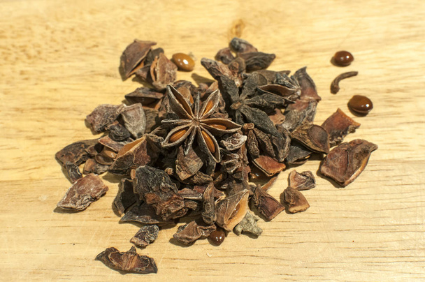 Uma pilha de sementes de anis estrela quebrada como close-up de especiarias no fundo da placa de madeira
 - Foto, Imagem