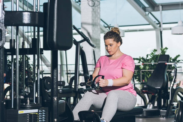 overgewicht vrouw uit te werken op training apparaat     - Foto, afbeelding