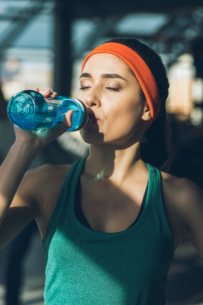 sporty woman drinking water at gym with closed eyes - Foto, imagen