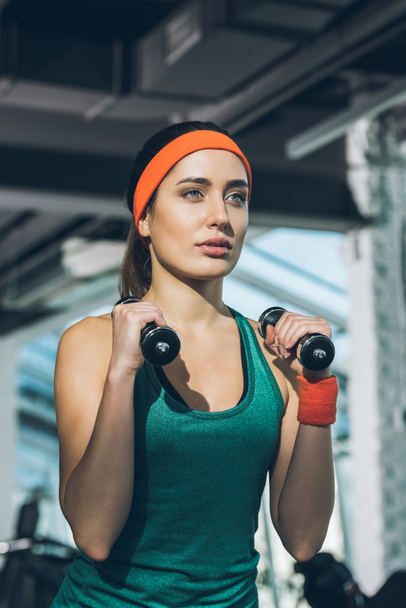 sporty woman training with dumbbells at gym - Photo, Image