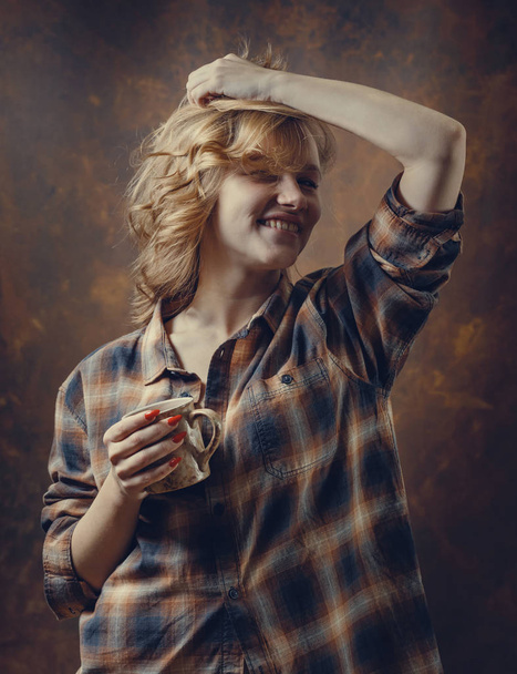  Jovem mulher bonita em camisa xadrez com caneca de café
 .  - Foto, Imagem
