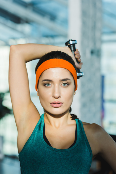 sporty woman training with dumbbell and looking at camera - Фото, зображення