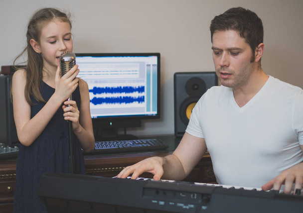 Άνθρωπος με κοριτσάκι πρόβες τραγούδι σε μουσική studio. - Φωτογραφία, εικόνα