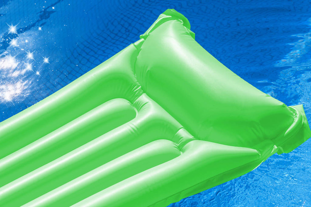 Zielony dmuchany materac pływające w basenie. - Zdjęcie, obraz