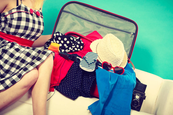 Woman choosing things to pack into suitcase - 写真・画像