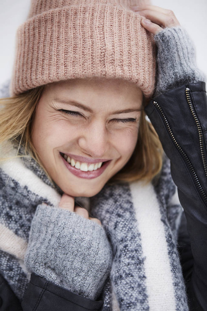 Portrait of young woman in winter clothing laughing with eyes closed - Fotoğraf, Görsel