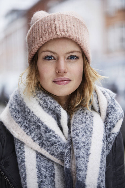 Portrait of young woman in pink hat and scarf looking at camera - Фото, зображення