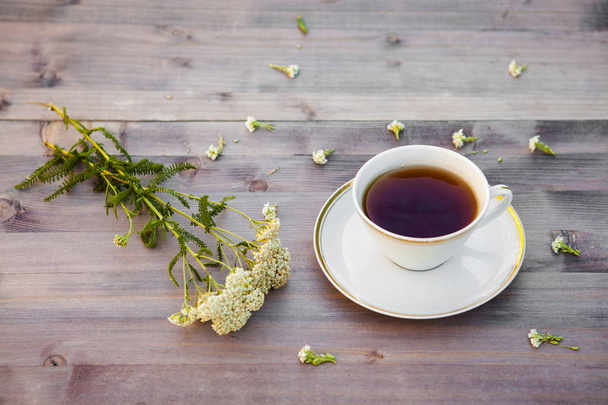 Cup of tea on a wooden table, with white flowers - Foto, Bild