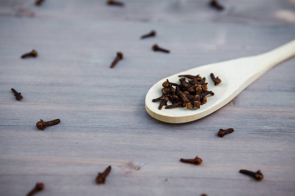 Seasoning cloves on a wooden spoon, background - Foto, immagini