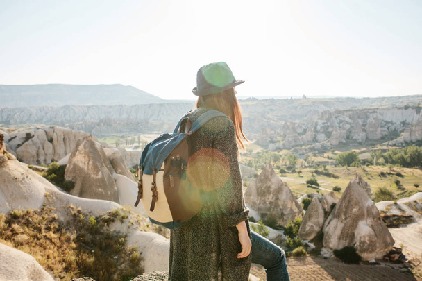 バックパックとの帽子の旅行者は山の上に立つ、トルコのカッパドキアの美しい景色に見えます。旅。ハイキング. - 写真・画像