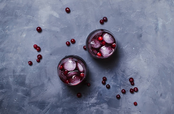 Alcohol cocktail with cranberries and ice, gray stone background, top view - Fotó, kép