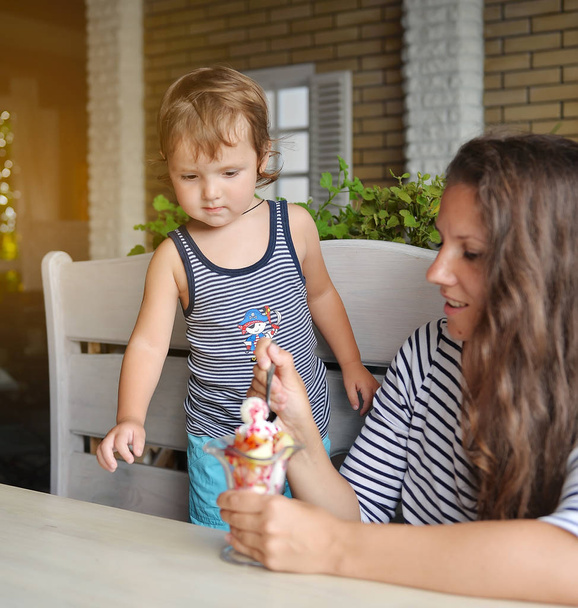 mamá alimenta a un hijo joven con helado en un café
 - Foto, Imagen