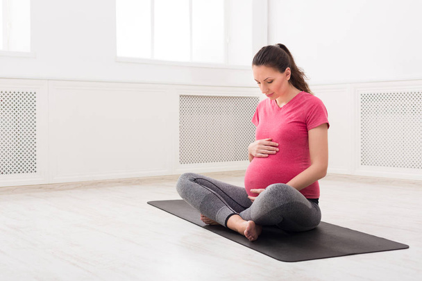 Chica embarazada sentada en pose de loto, acariciar su vientre
 - Foto, imagen