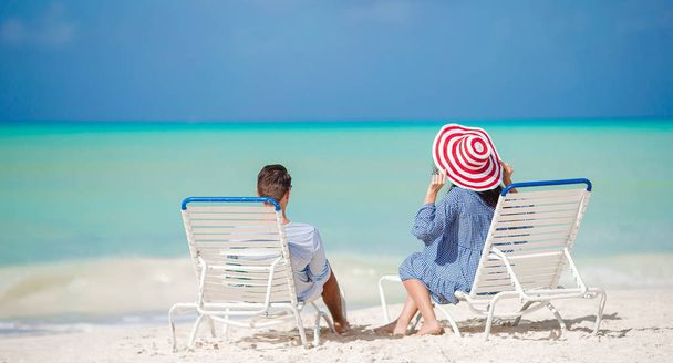 Ευτυχισμένο ζευγάρι χαλαρώνοντας σε μια τροπική παραλία στην ξαπλώστρα - Φωτογραφία, εικόνα