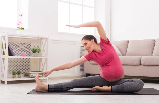 Pregnant woman stretching training indoors - Photo, Image