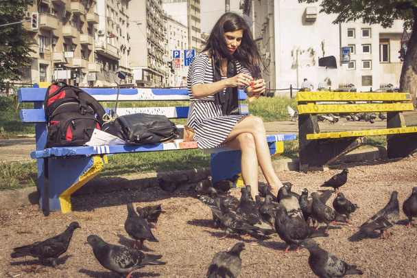 Young woman feeding pigeons in the park - Fotografie, Obrázek