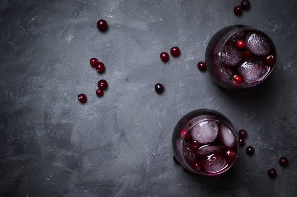 Alcohol cocktail with cranberries and ice, gray stone background, top view - 写真・画像
