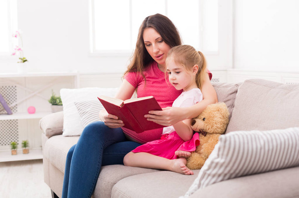 Petite fille et sa mère lisant le livre à la maison
 - Photo, image