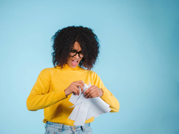 Breaking contract. Furious young african american woman with afro hairstyle tearing up paper on blue background. - Fotografie, Obrázek