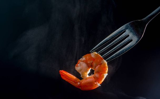 Steamed shrimp on fork isolated on dark background with copy space. Seafood buffet in restaurant concept. Use for seafood buffet promotions advertising - Foto, Imagem