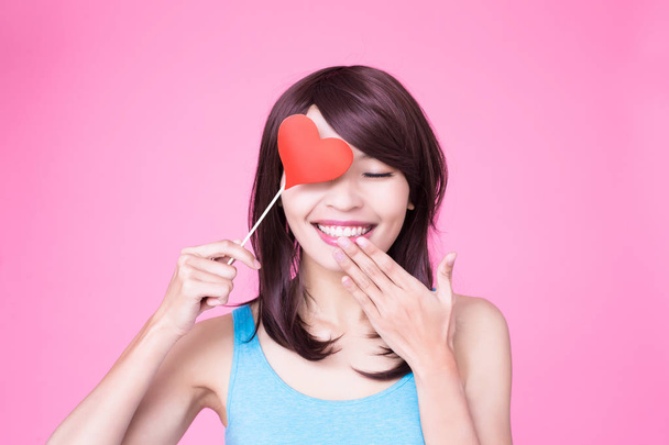 woman holding red love heart over eye on the pink background - Foto, afbeelding