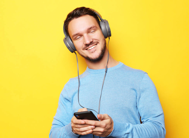 young man wearing headphones and holding mobile phone - Foto, imagen