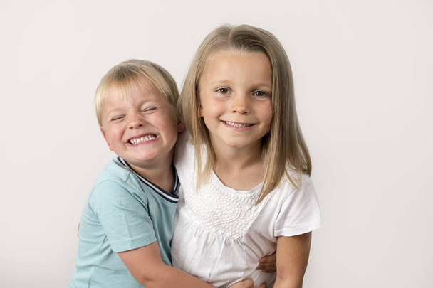7 years old adorable blond happy girl posing with her little 3 years old brother smiling cheerful isolated on white background - 写真・画像