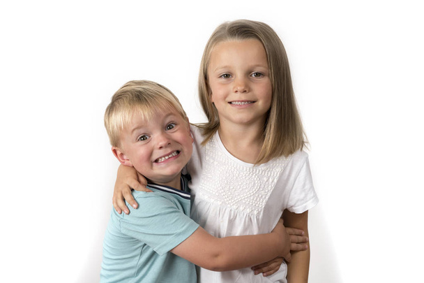 7 éves imádnivaló szőke boldog lány pózol, ő kis 3 éves régi testvérének, mosolygós vidám elszigetelt fehér background - Fotó, kép