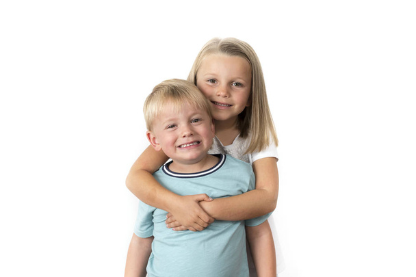 7 let rozkošný blond šťastná dívka pózuje s její malou 3 roky starý bratr s úsměvem veselá izolovaných na bílém pozadí - Fotografie, Obrázek