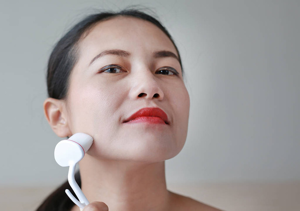 Portrait of beautiful woman using fine make up brush for face massage. Beauty Concept. - Fotografie, Obrázek