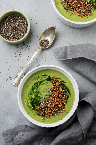 Useful smoothies from spinach with buckwheat flakes in ceramic bowls on gray concrete table background. Selective focus. Top view. Copy space. - Foto, Bild