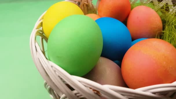 Easter color pastel eggs in basket. Close up on green background. - Felvétel, videó