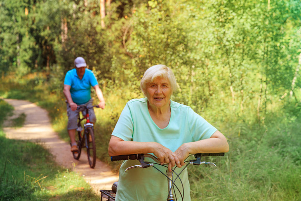 happy senior couple riding bikes in nature - Photo, Image