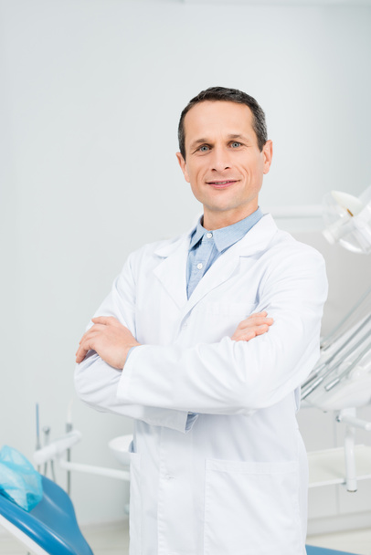 Confident doctor with folded arms in modern dental clinic - Zdjęcie, obraz