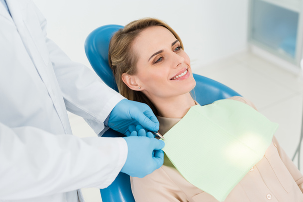 Lekarz, ustalające kobiece serwetka pacjenta w nowoczesny gabinet stomatologiczny - Zdjęcie, obraz
