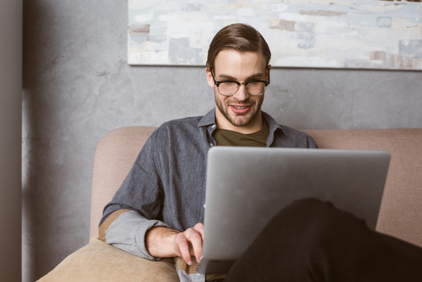 heureux jeune homme d'affaires travaillant avec ordinateur portable sur le canapé
 - Photo, image