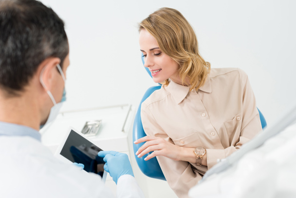 Médico masculino e paciente feminino olhando para tela tablet na clínica odontológica moderna
 - Foto, Imagem