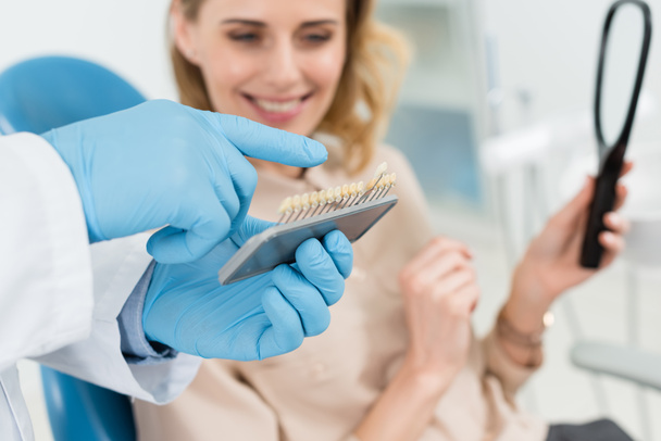 Médico eligiendo implantes dentales con paciente femenino en clínica dental moderna
 - Foto, imagen