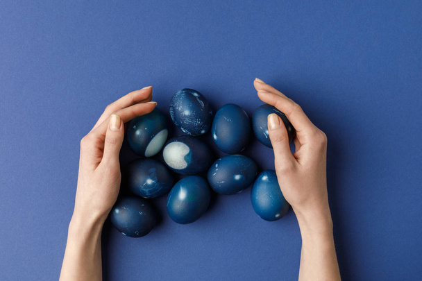 imagen recortada de la mujer tocando huevos de Pascua pintados de azul
 - Foto, Imagen