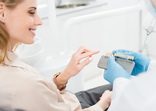 モダンな歯科医院で女性患者に歯のインプラントを示す医師 - 写真・画像