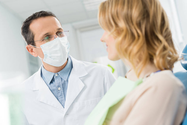Frau berät sich mit Arzt in moderner Zahnklinik - Foto, Bild