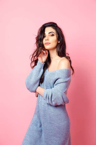 Portrait of expressive young model in blue knitted sweater on pink studio background - Photo, Image