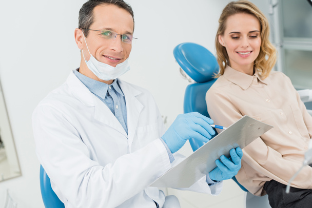 Diagnóstico de registro médico mientras consulta con paciente en clínica dental moderna
 - Foto, Imagen