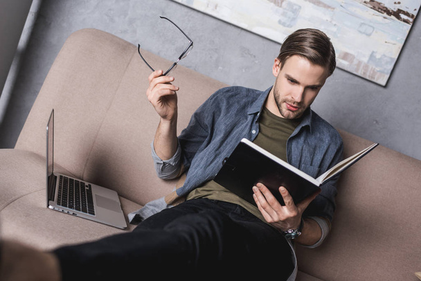 young serious businessman reading notes on couch - Photo, Image