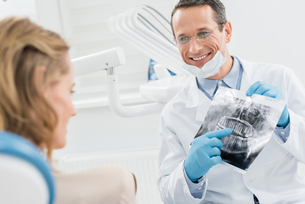 Odontoiatra che mostra la radiografia del paziente femminile nella moderna clinica dentale
 - Foto, immagini